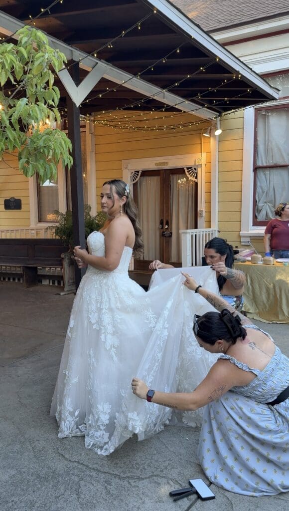 Wedding content creator assisting a bride with her wedding dress before portraits, demonstrating the trust and support that create an exceptional client experience.